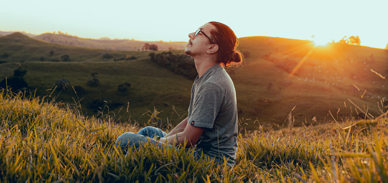 Man meditating in the countryside with sunset in background